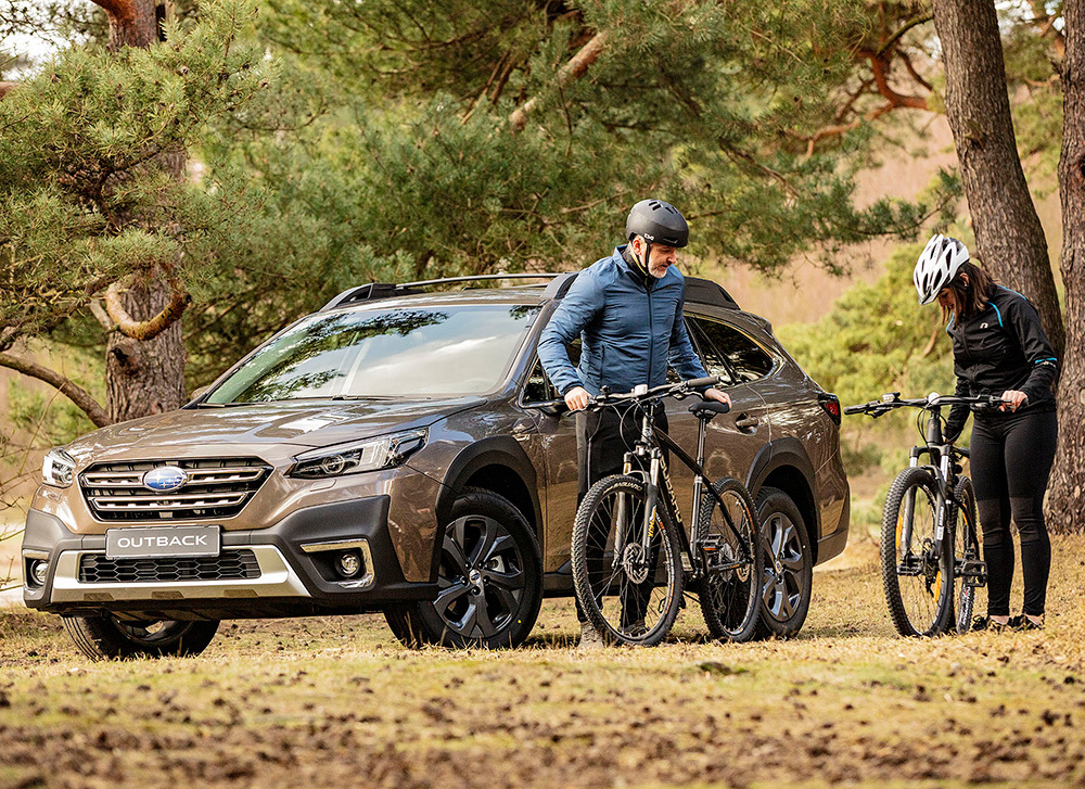 Subaru Outback i skogen med två mountainbikes – perfekt kombination av fyrhjulsdrift, lastutrymme och aktiv livsstil.