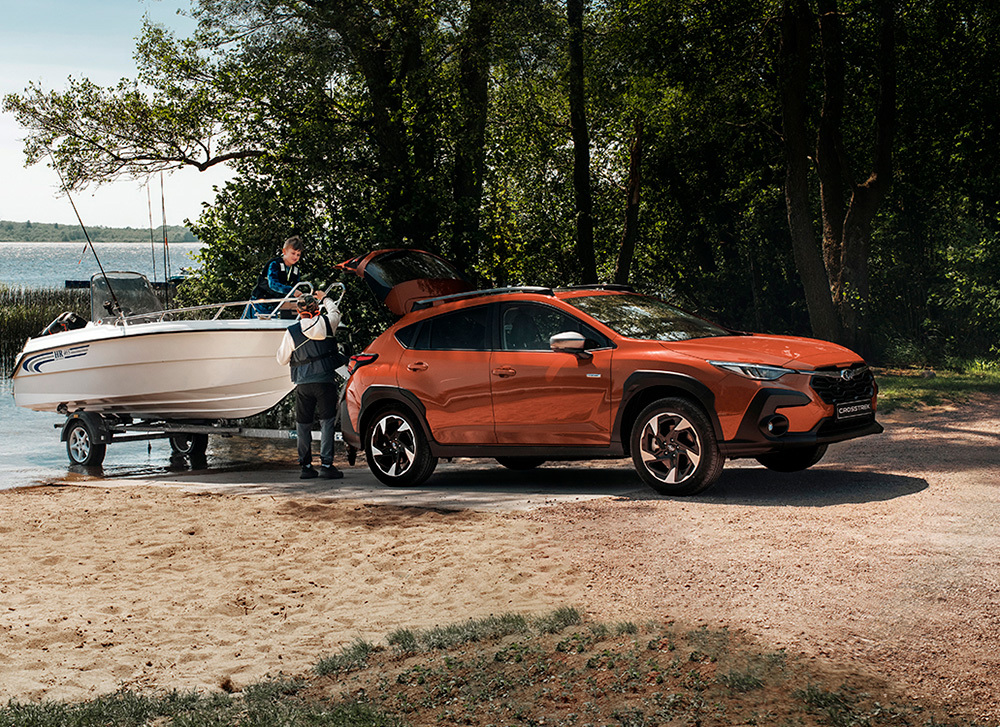 Subaru Crosstrek backar ner i vattnet och sjösätter en motorbåt från en båttrailer.
