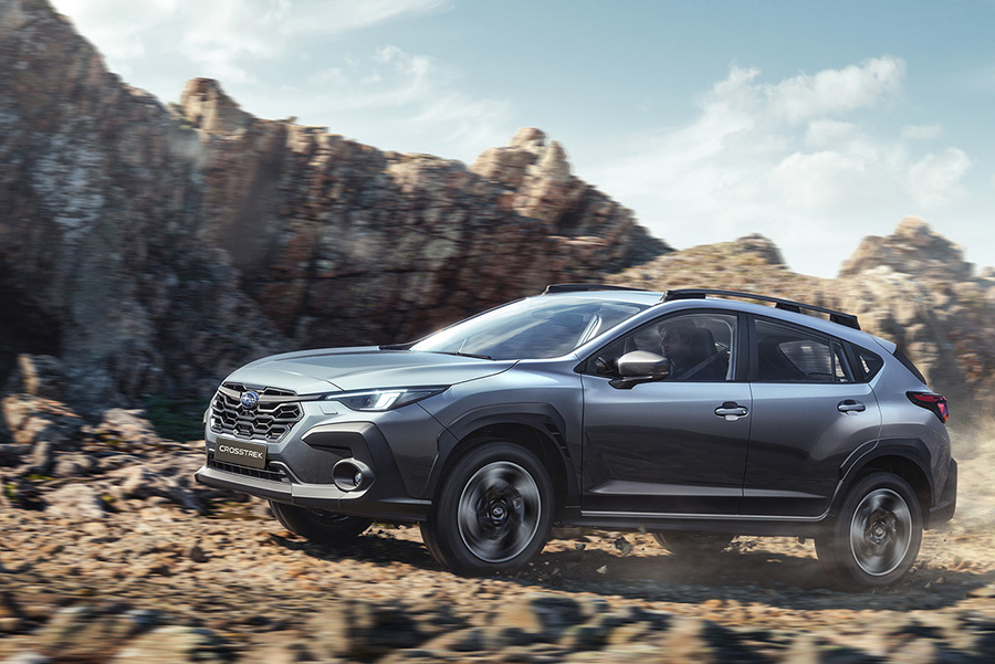 Subaru Crosstrek kör på en grusväg, med dammoln som yr bakom bilen.