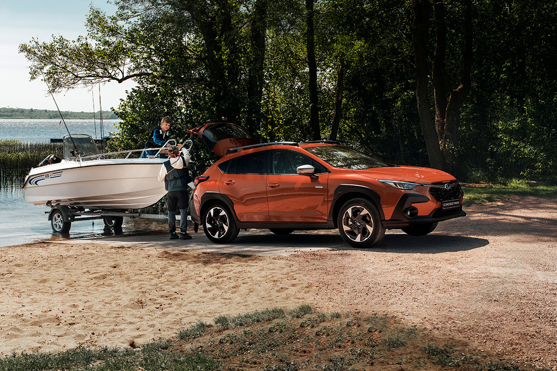 Subaru Crosstrek med båt på trailer vid strandkanten – kombinerar fyrhjulsdrift, dragförmåga och äventyrslust i ett kompakt och kapabelt format.