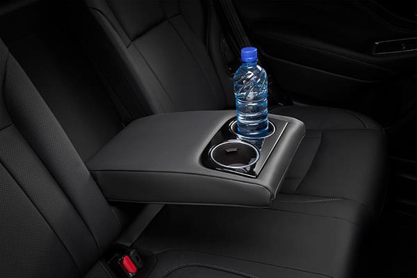 Nedfällbart armstöd med integrerade kopphållare i baksätet på en Subaru.