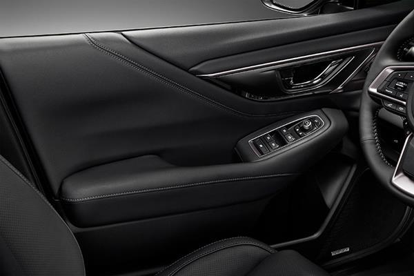 Insidan av förardörren i Subaru med armstöd och knappar för elhissar och spegelinställning.